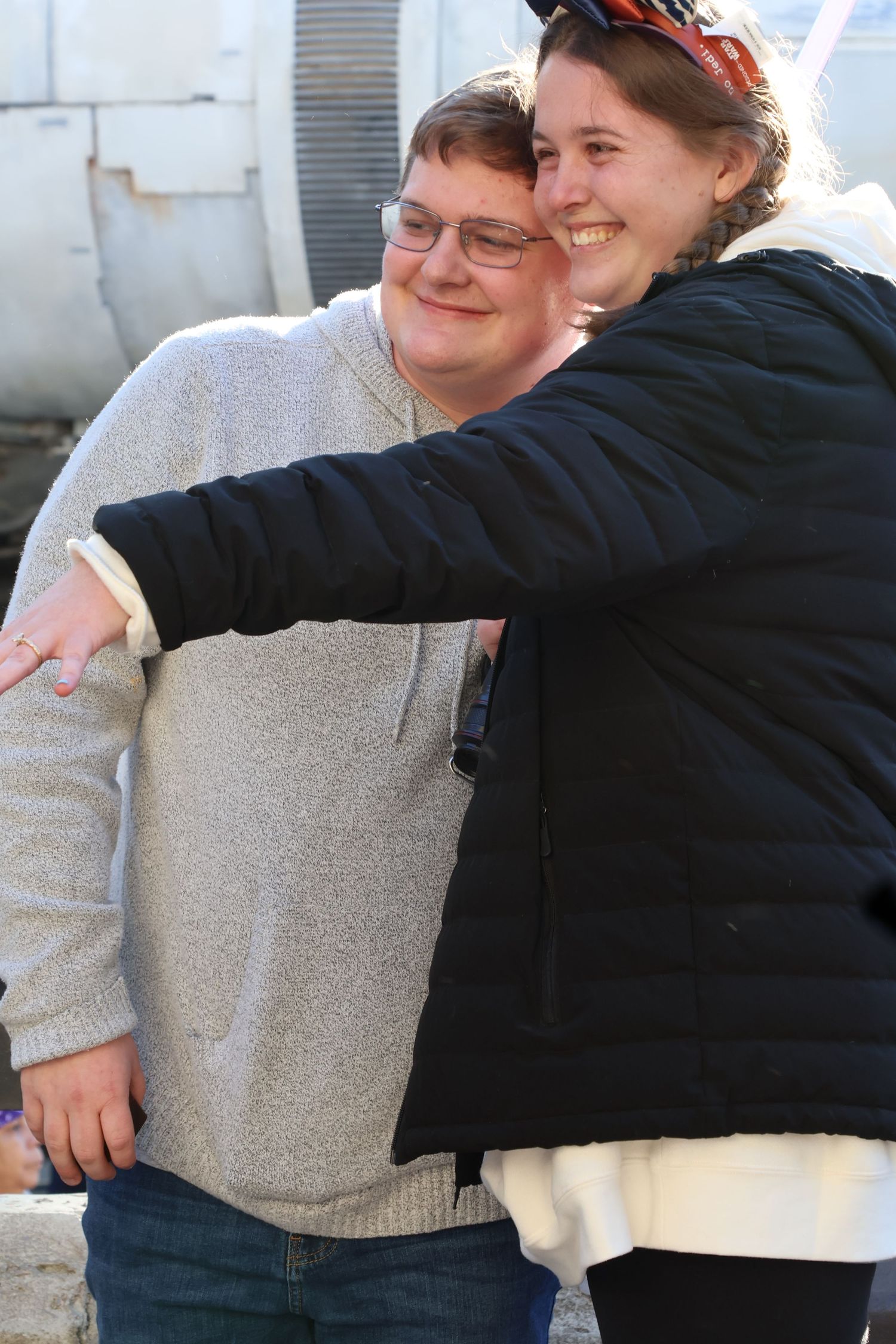 Smiling couple poses together as one partner extends a hand to show a ring.