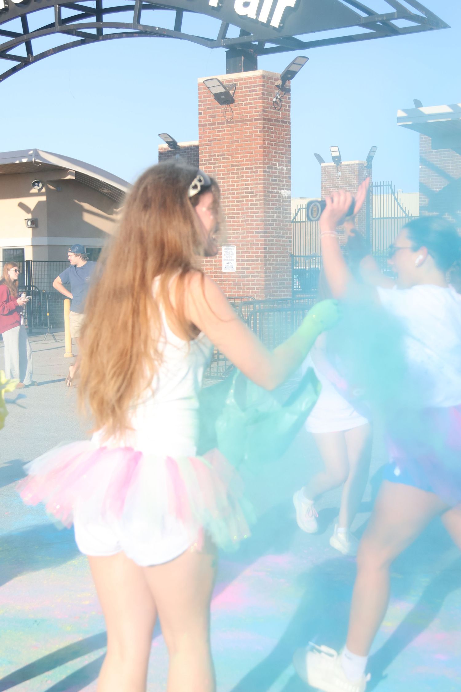 Participant tosses blue powder across a color-covered street during a color run.