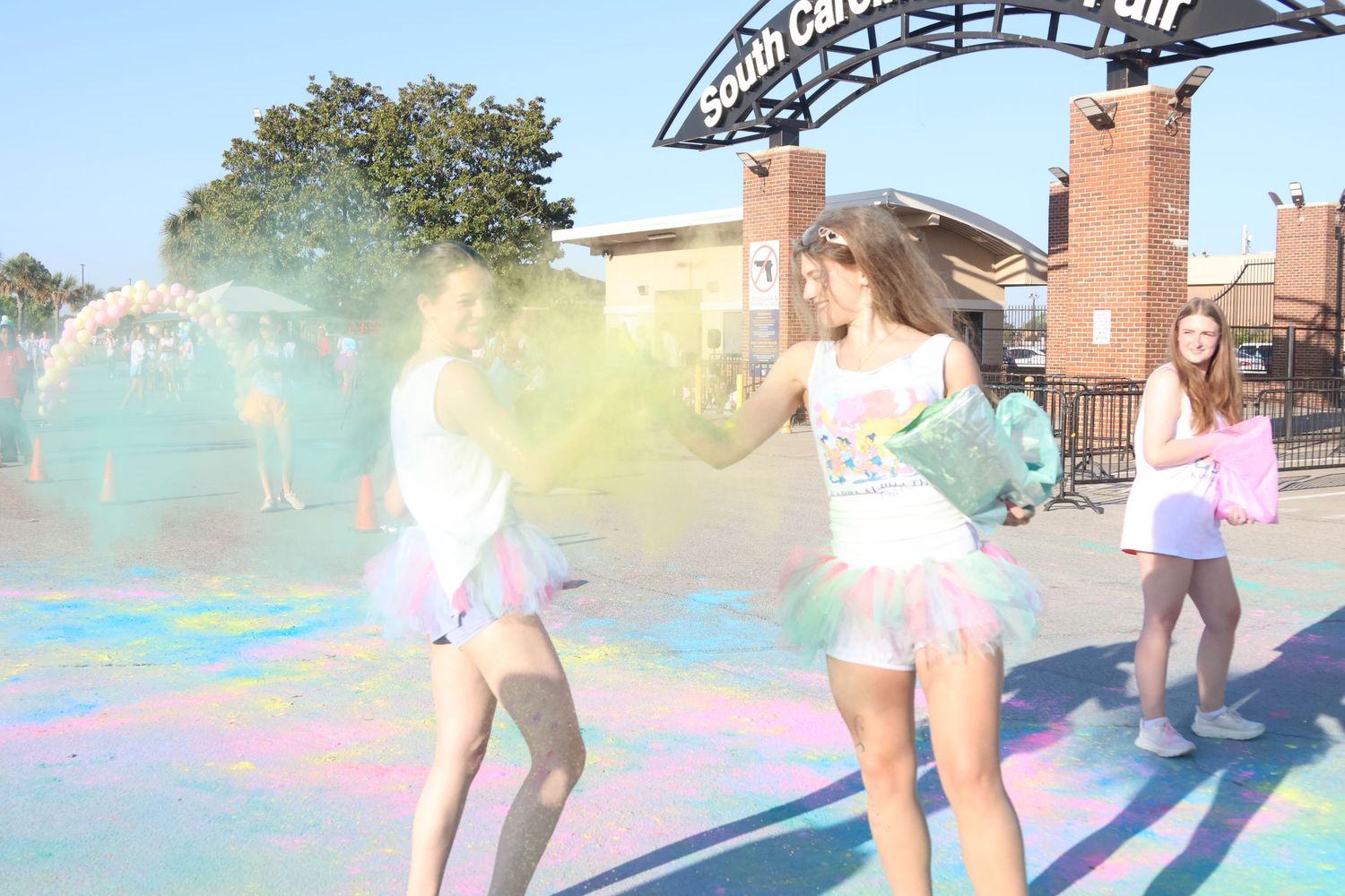 Two participants run through yellow and blue powder near the finish of a color run.