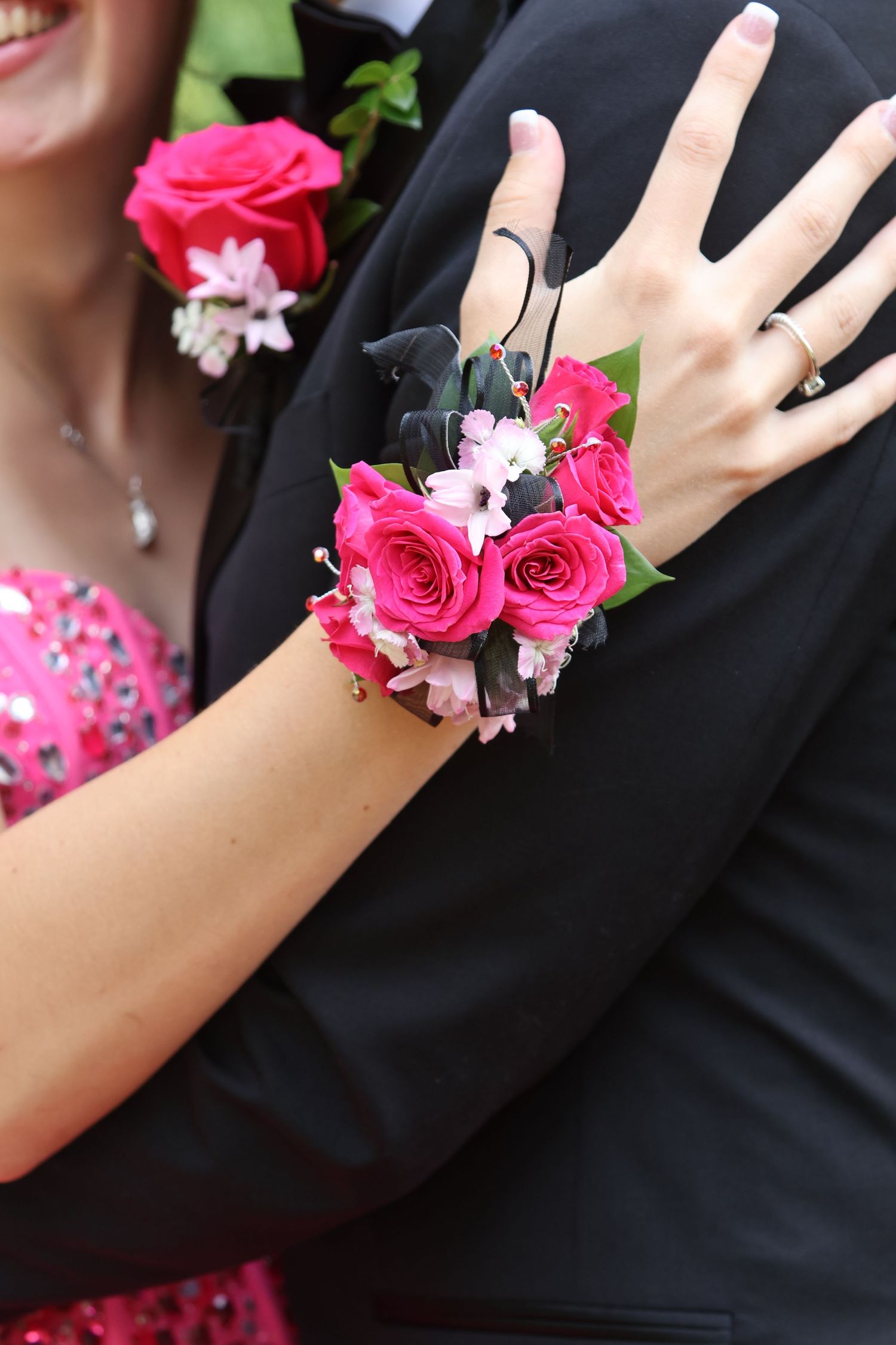 Close-up of a pink floral wrist corsage resting on a black suit jacket.