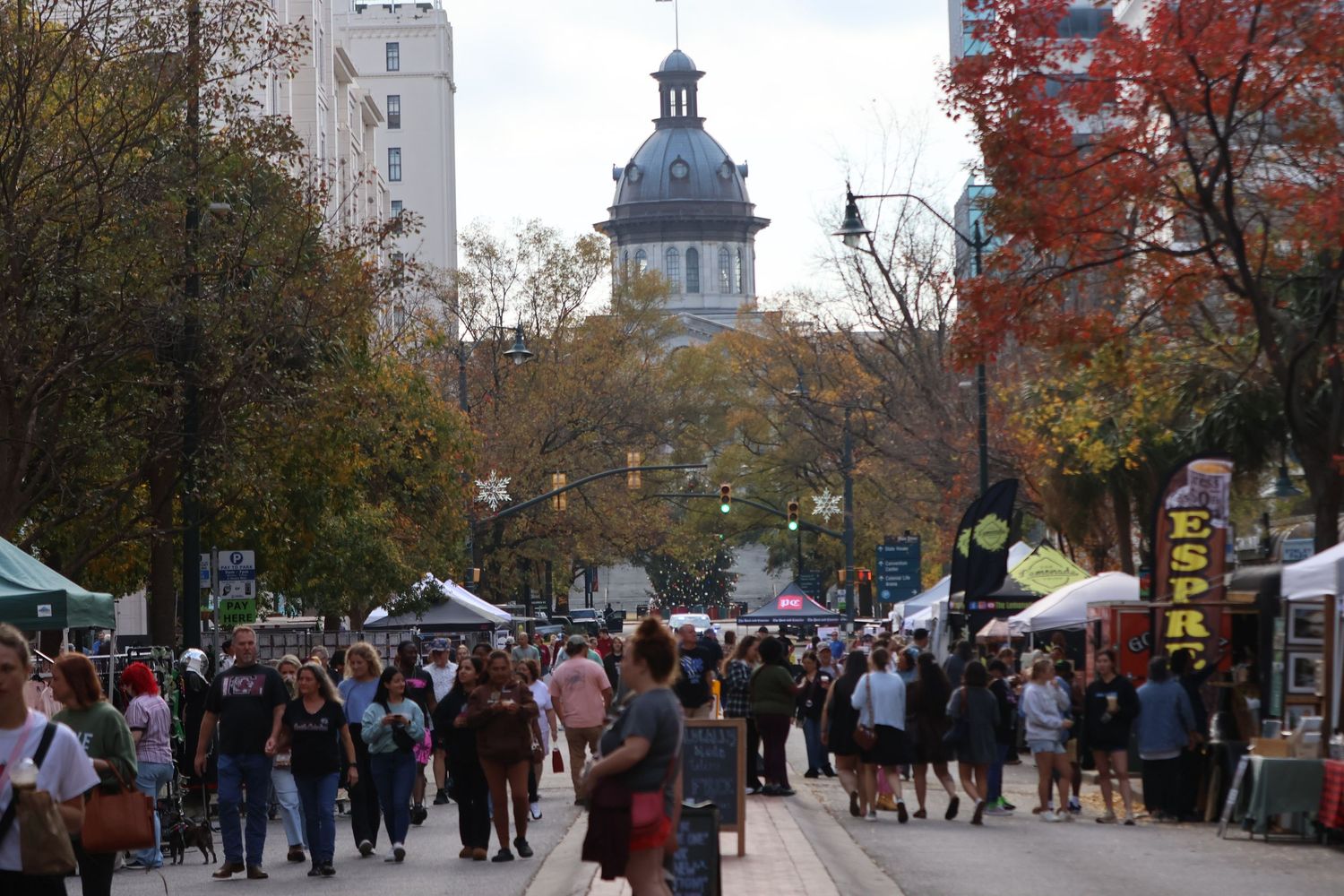Crowds browse vendor tents along a downtown street during a fall festival.