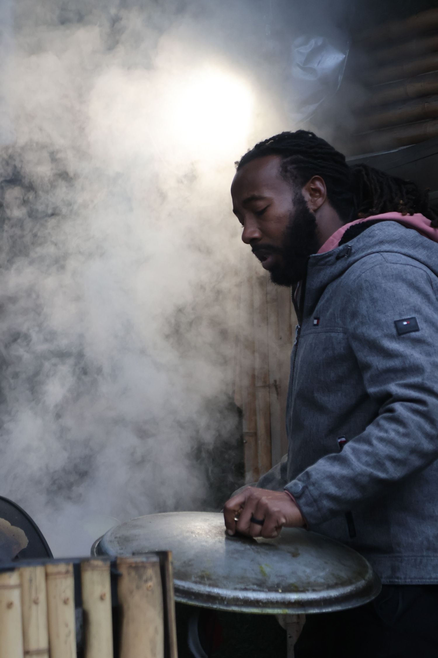 Man tends a smoking outdoor grill during a community event.