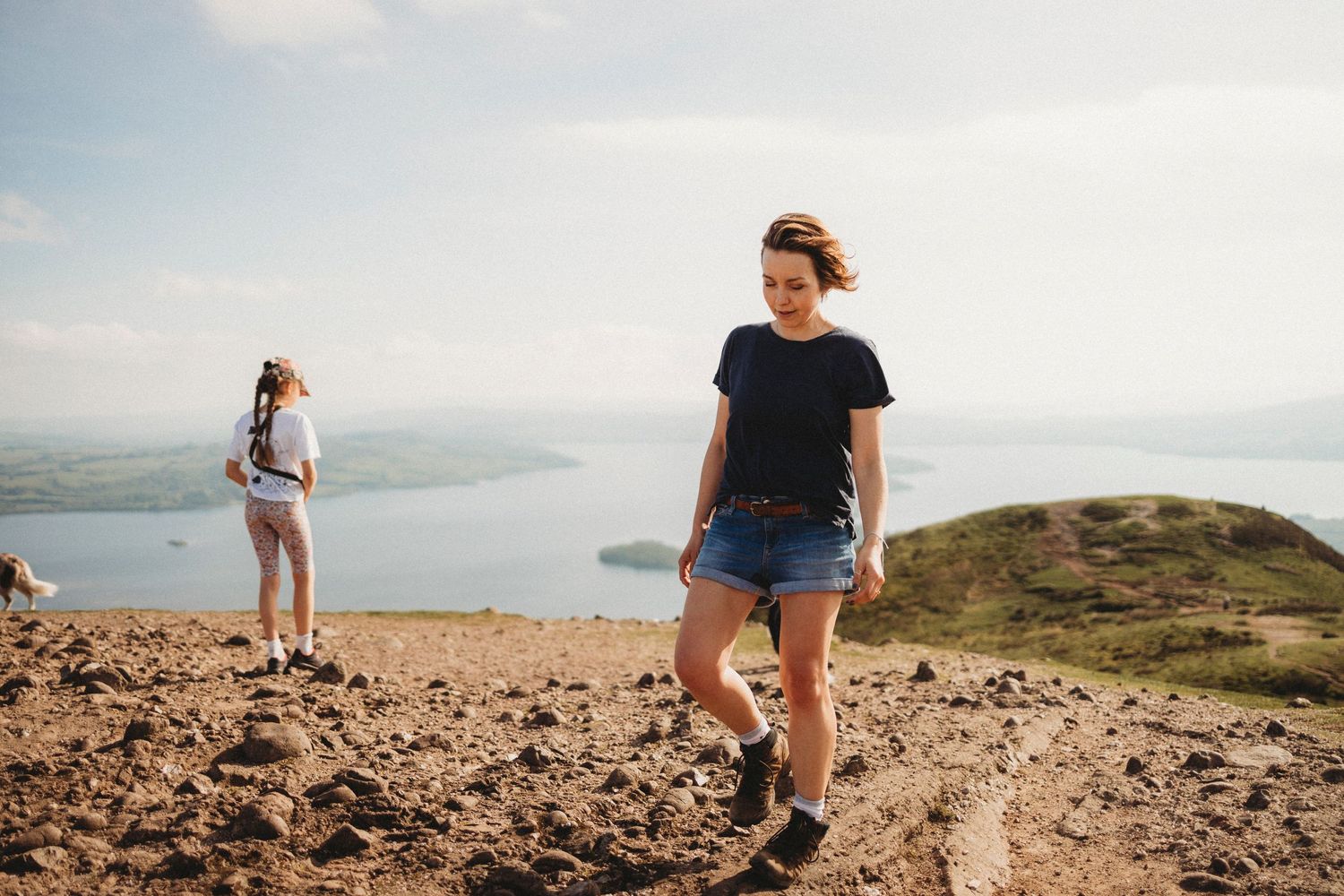 Hikers enjoying scenic views from a hilltop overlooking a misty landscape and water below.