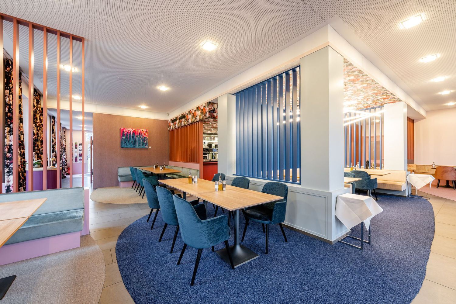 Modern office interior with blue chairs and wooden dividers creating collaborative workspace.