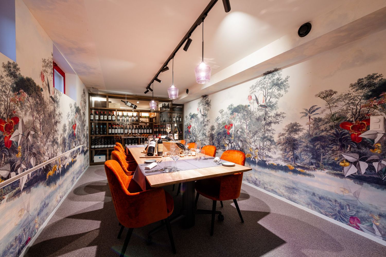 Elegant dining room with blue wall murals and orange velvet chairs features modern track lighting and table settings.