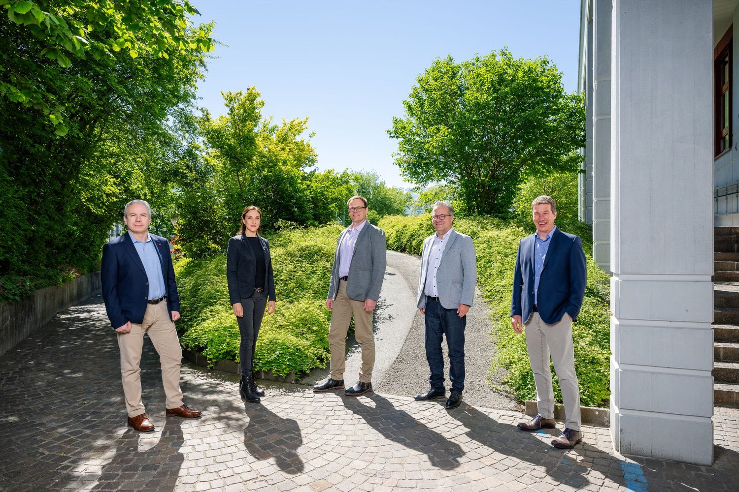 Group of business professionals having outdoor meeting on sunny day near building.
