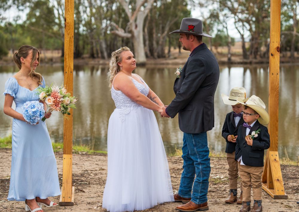 Outdoor country wedding ceremony by a lake with guests in casual attire.