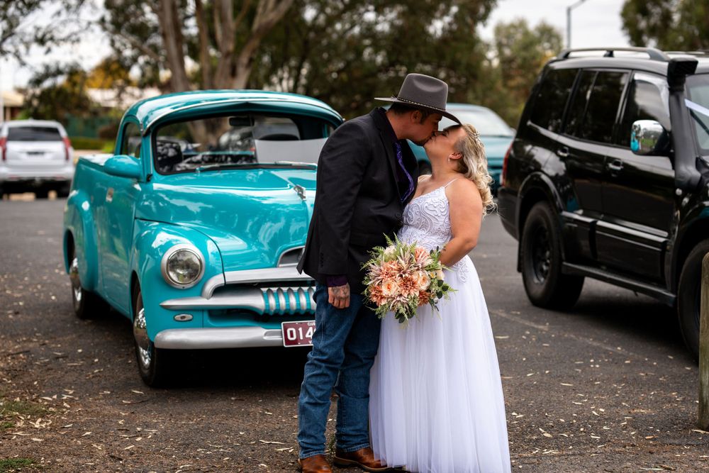 Wedding couple posing in front of classic turquoise vintage car.