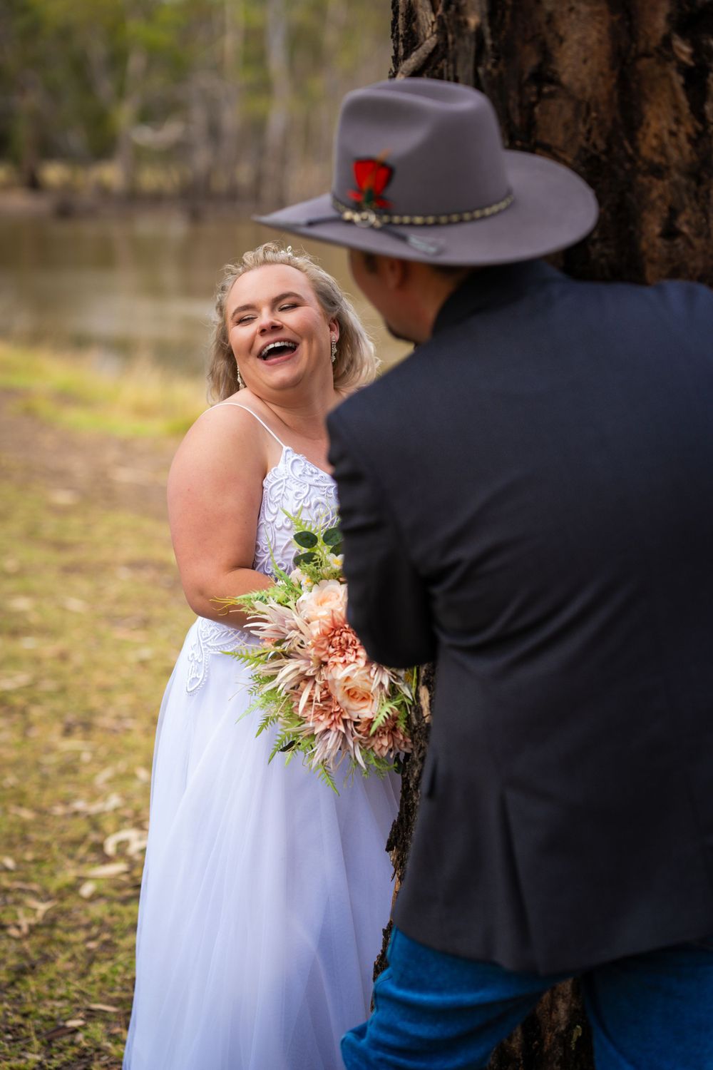 Candid moment between newlyweds during outdoor lakeside photoshoot.