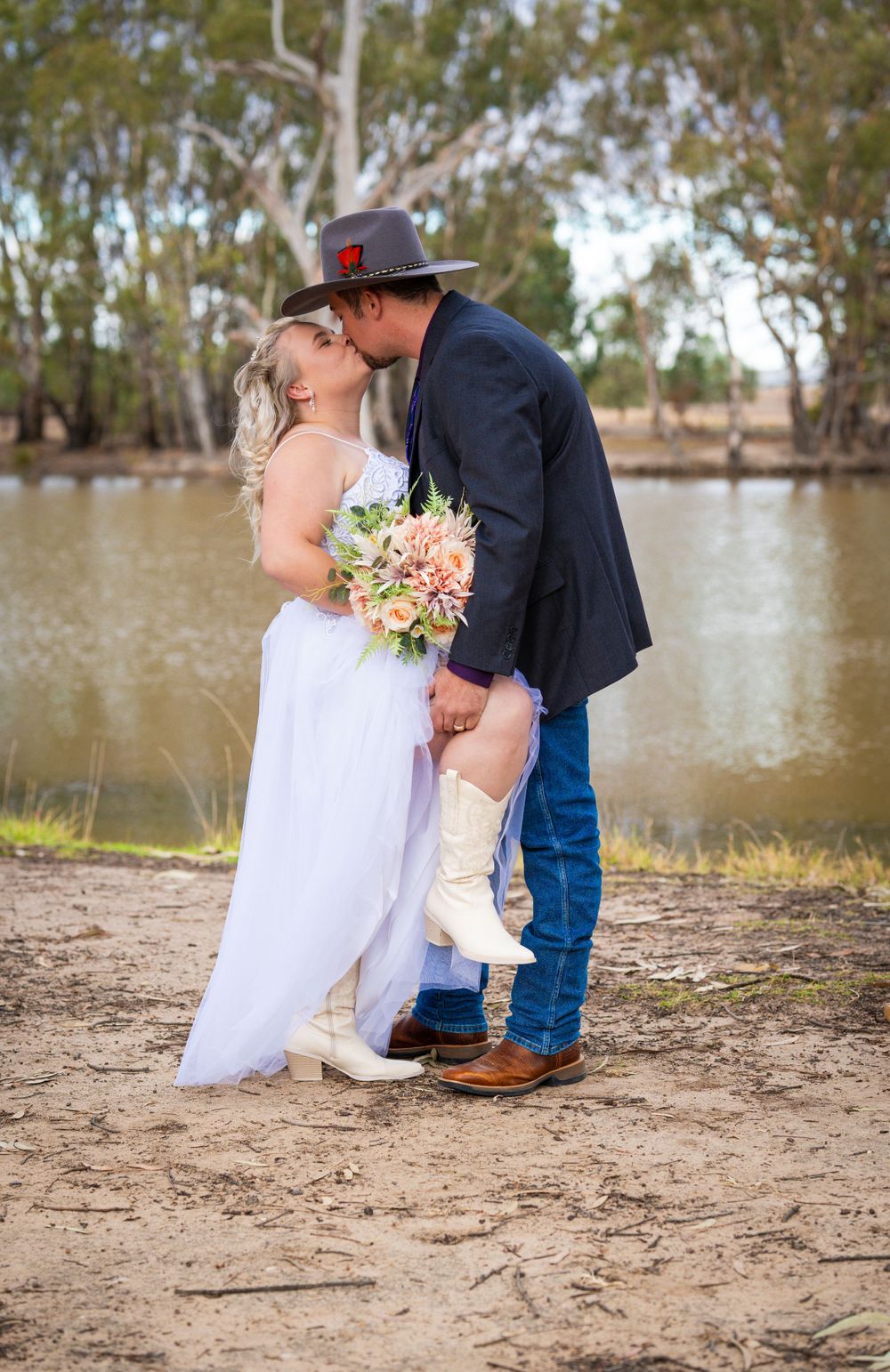 An intimate wedding moment captured by a scenic waterfront with gum trees.