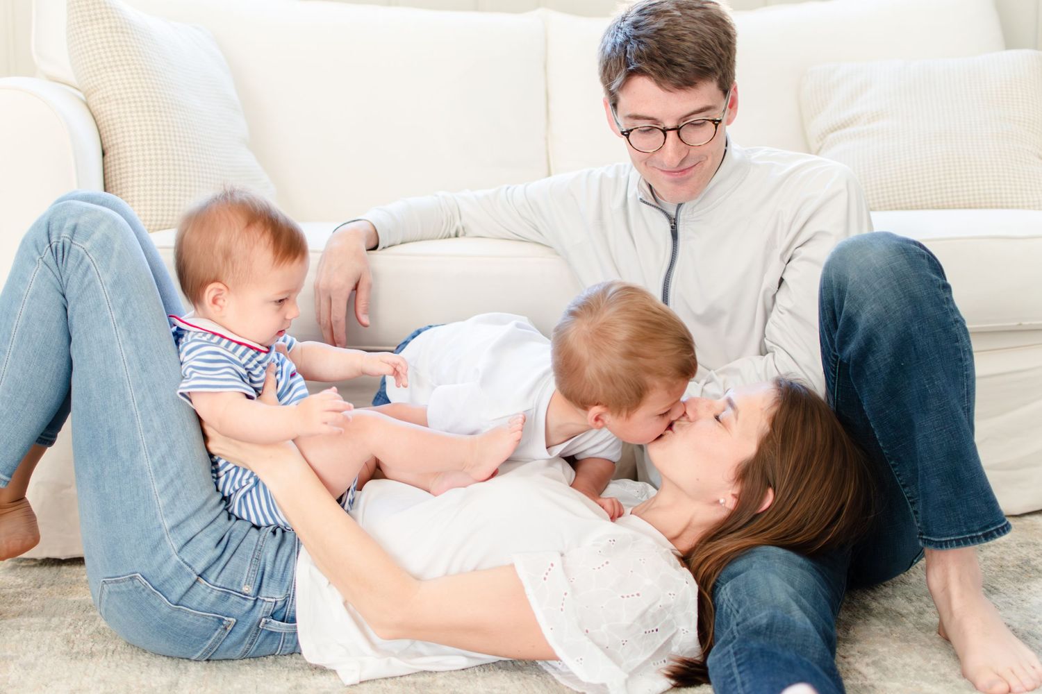A young Ardmore family playfully snuggles together on the couch in their living room.