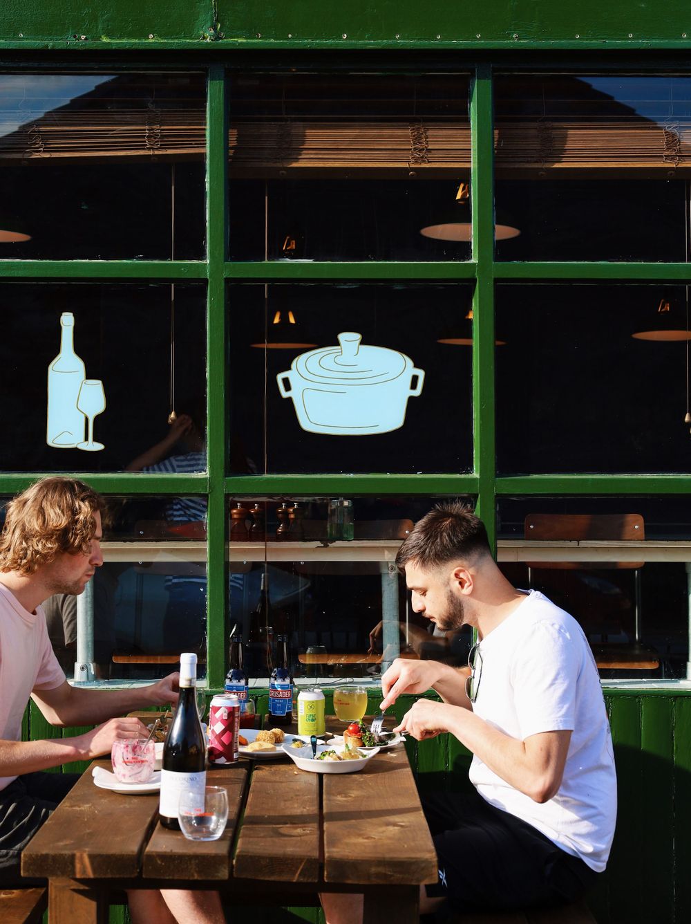Diners enjoying a meal at a restaurant with green paneled walls and natural lighting.