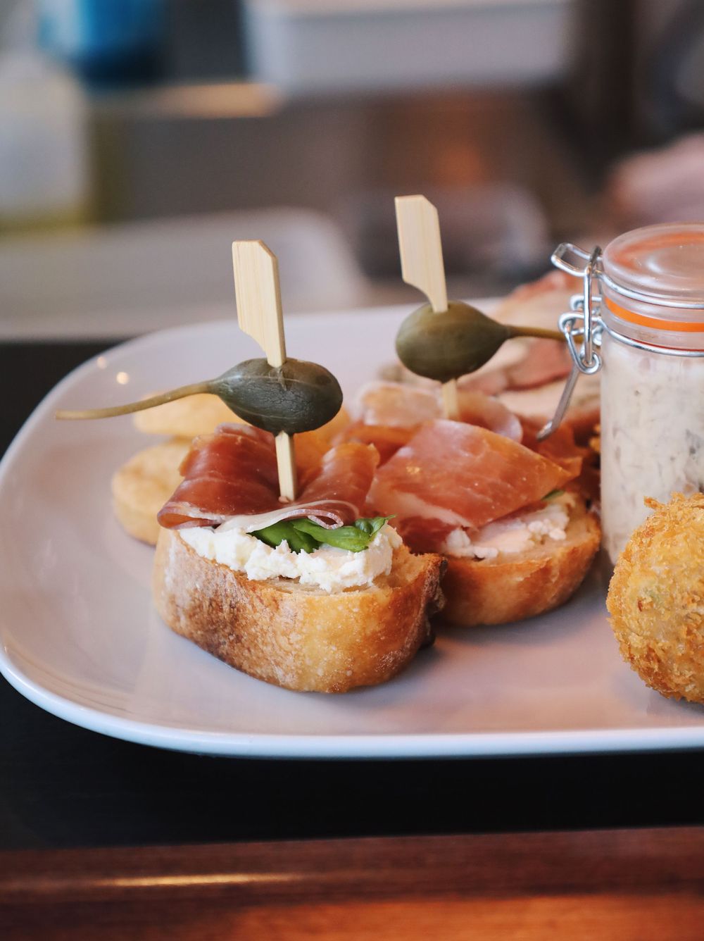 Close-up of appetizers being assembled on white plates with wooden toothpicks.