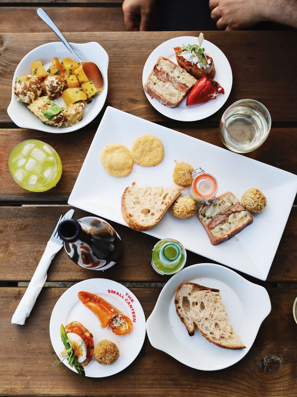 Various plates of food and appetizers arranged on a rustic wooden table at a restaurant.