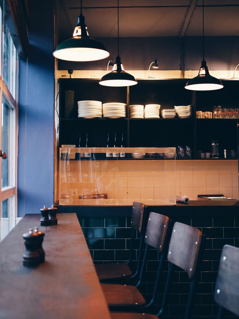 Modern restaurant interior with dark leather seating and industrial pendant lighting.