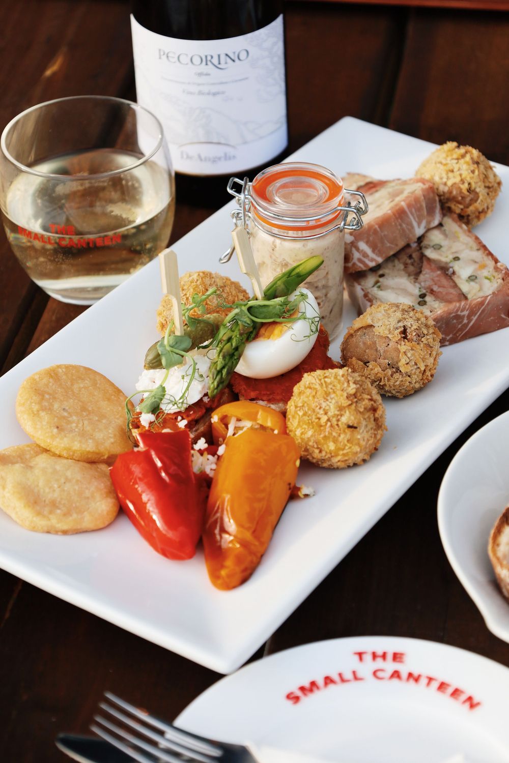 Restaurant platter with assorted appetizers including eggs, vegetables and croquettes.