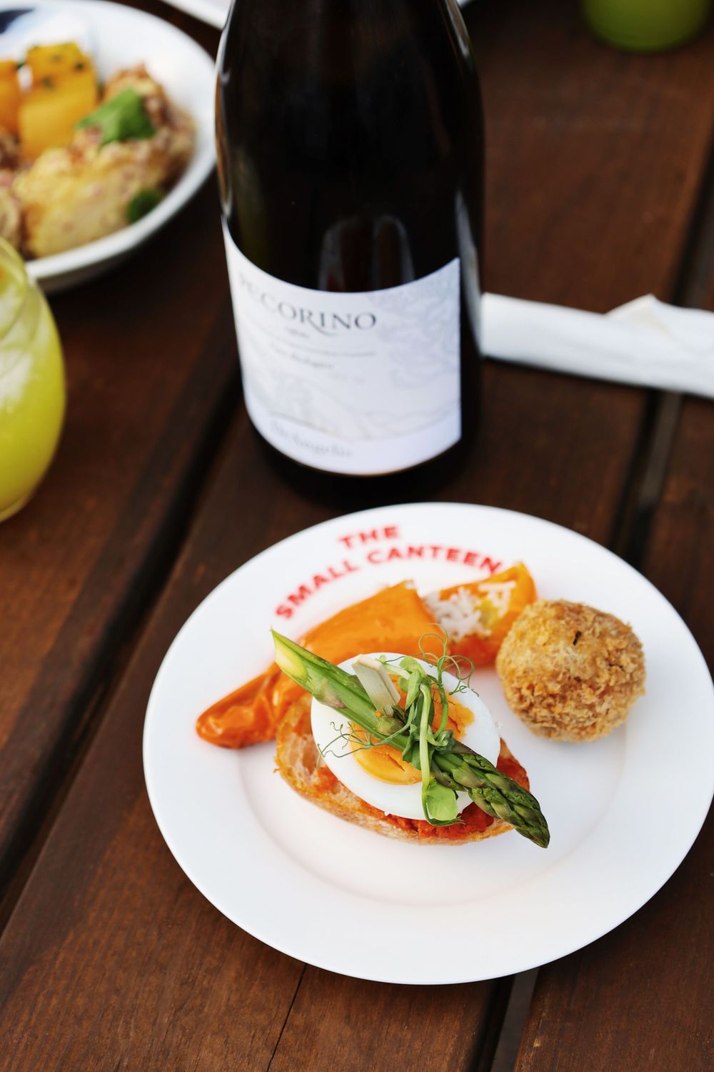 Fine dining plate featuring eggs, vegetables and breaded items with wine glass.