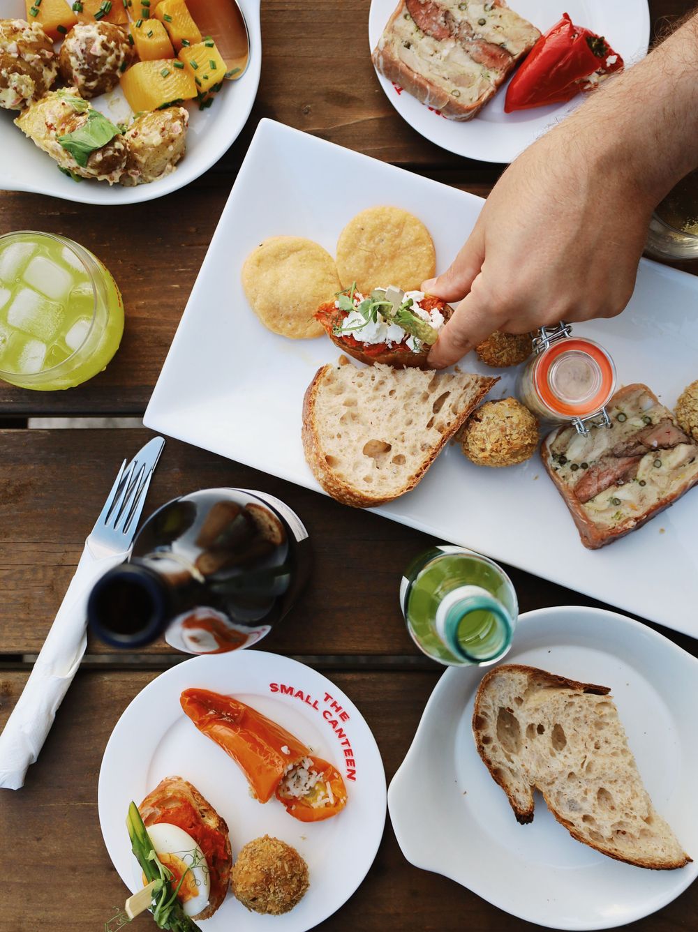 Overhead view of various appetizers and sandwiches being served on white plates at a casual restaurant.