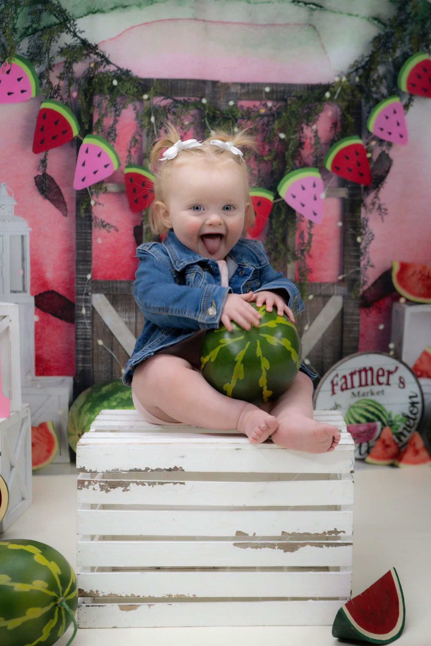A pink and white first birthday setup with a smiling baby in tulle dress next to an ombre cake and peach decor.
