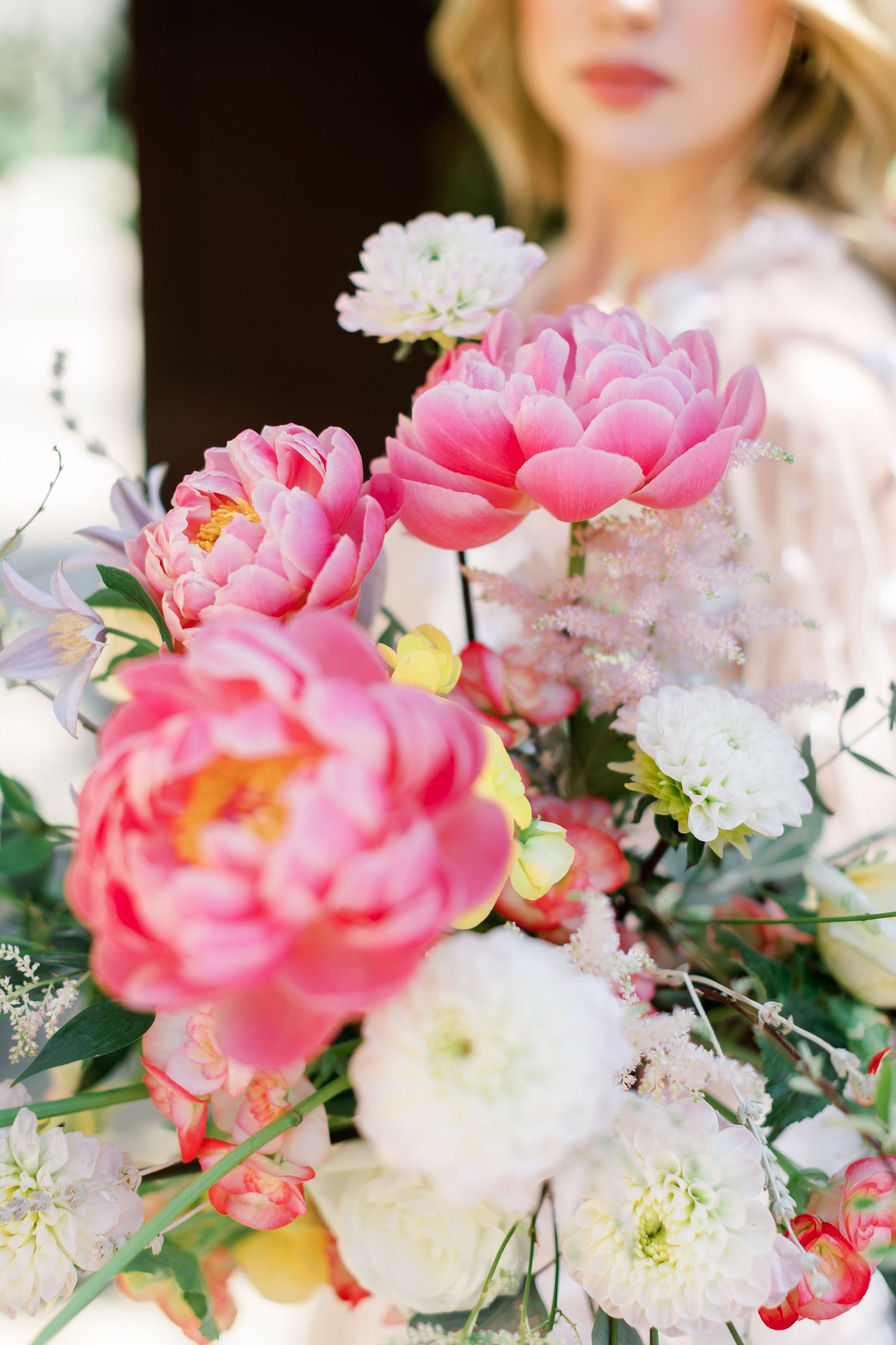Close-up of a luxurious bouquet featuring pink peonies and white flowers with delicate greenery.