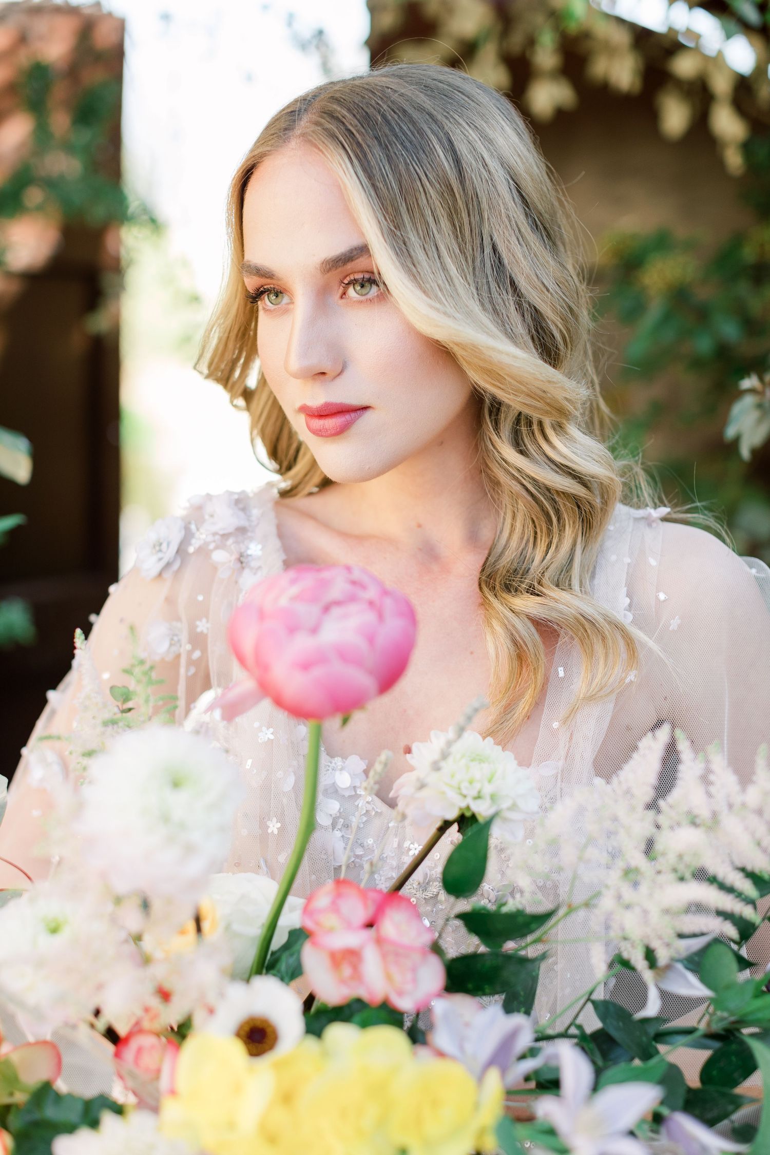 Romantic spring wedding portrait with pink peonies and delicate lace details in soft natural lighting.