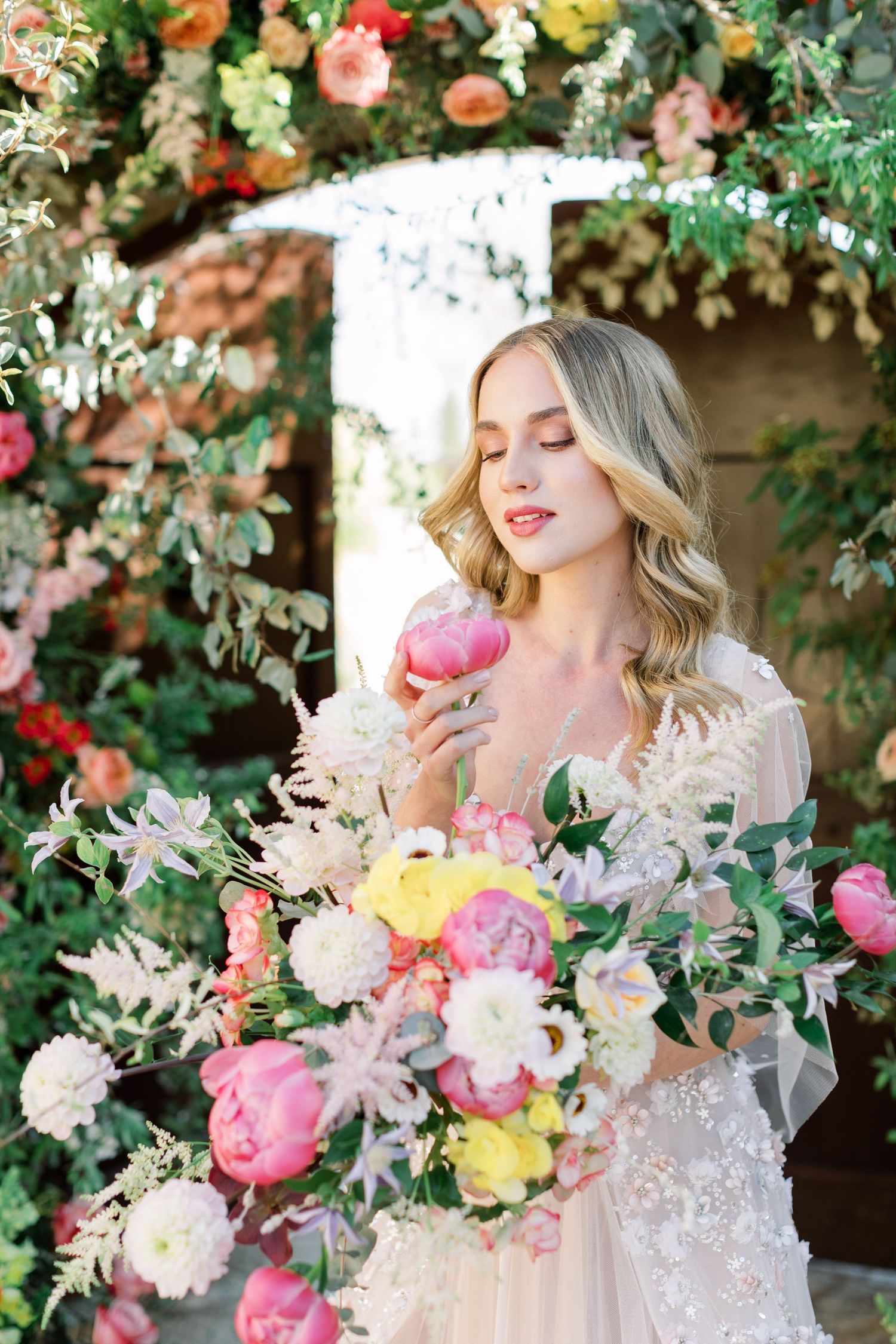 Ethereal bridal portrait in a garden with cascading florals and pink peonies in a dreamy setting.