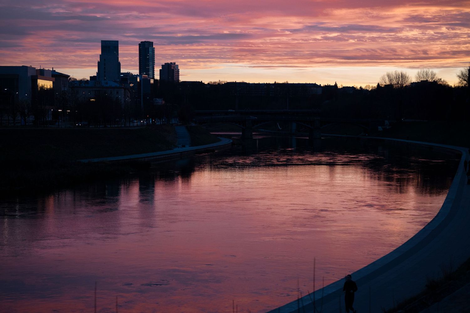 Pink-violet evening landscape of Vilnius, located in Lithuania. The river, sunset, skyscrapers, clouds.
