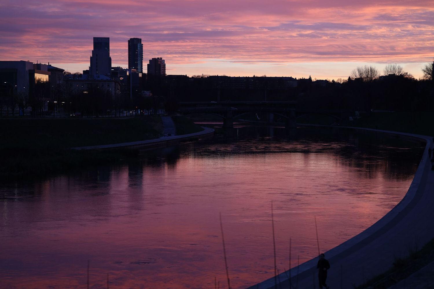 Pink-violet evening landscape of Vilnius, located in Lithuania. The river, sunset, skyscrapers, clouds.