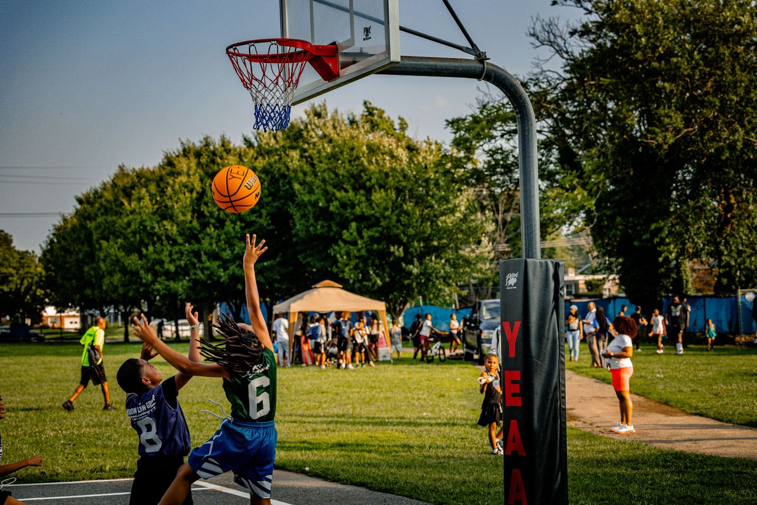 Players dribbling and shooting basketballs at outdoor hoops during a community event.