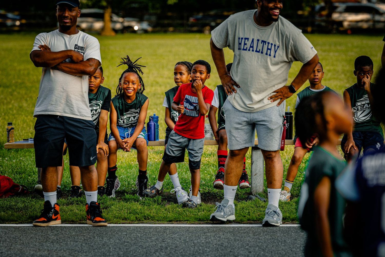 Coaches and young players gather on a basketball court during a summer sports program.