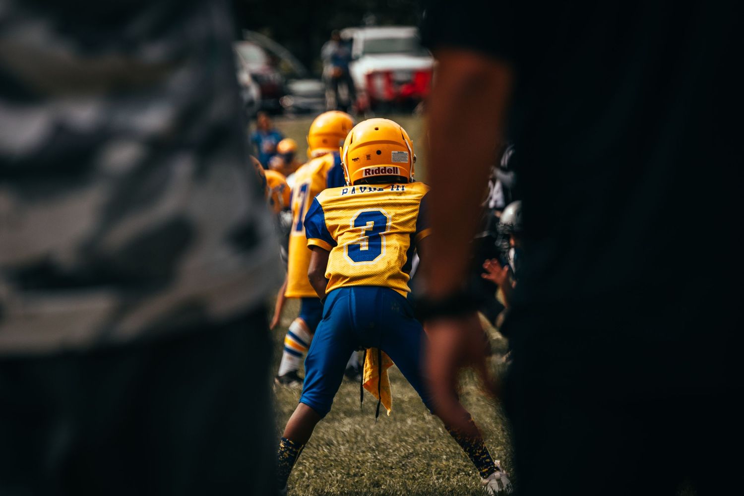 Player wearing yellow jersey number 3 stands ready on the football field.