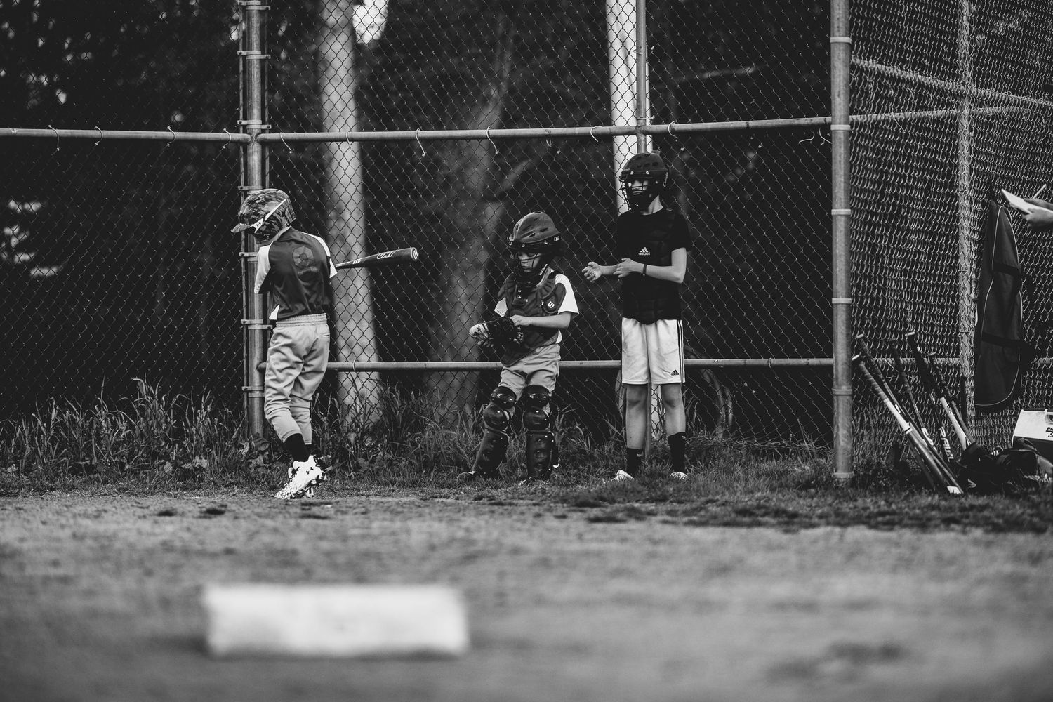 Black and white image of baseball field with chain link fence in background.
