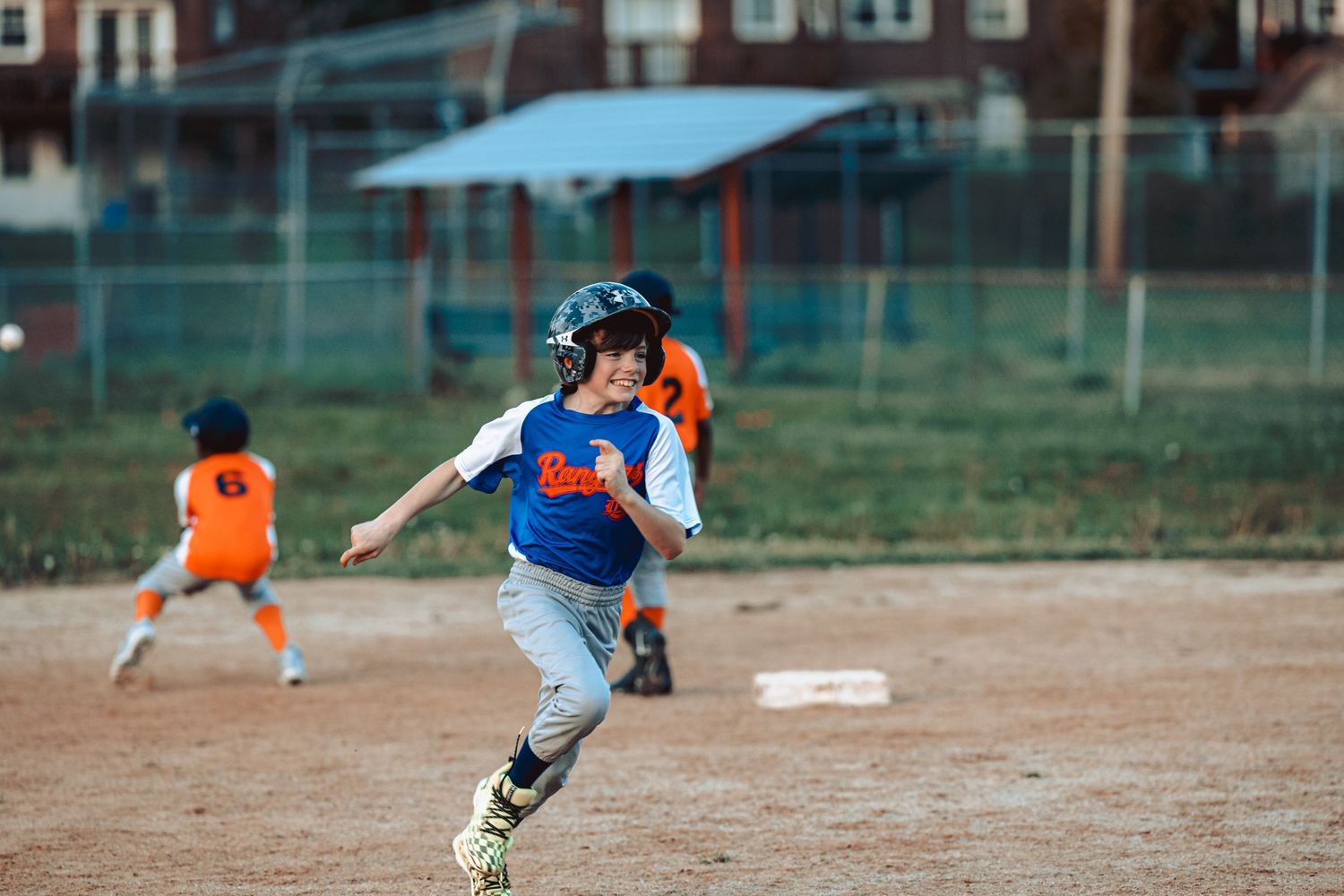 Baseball players running on a dirt field during practice with spectators watching from the sidelines.