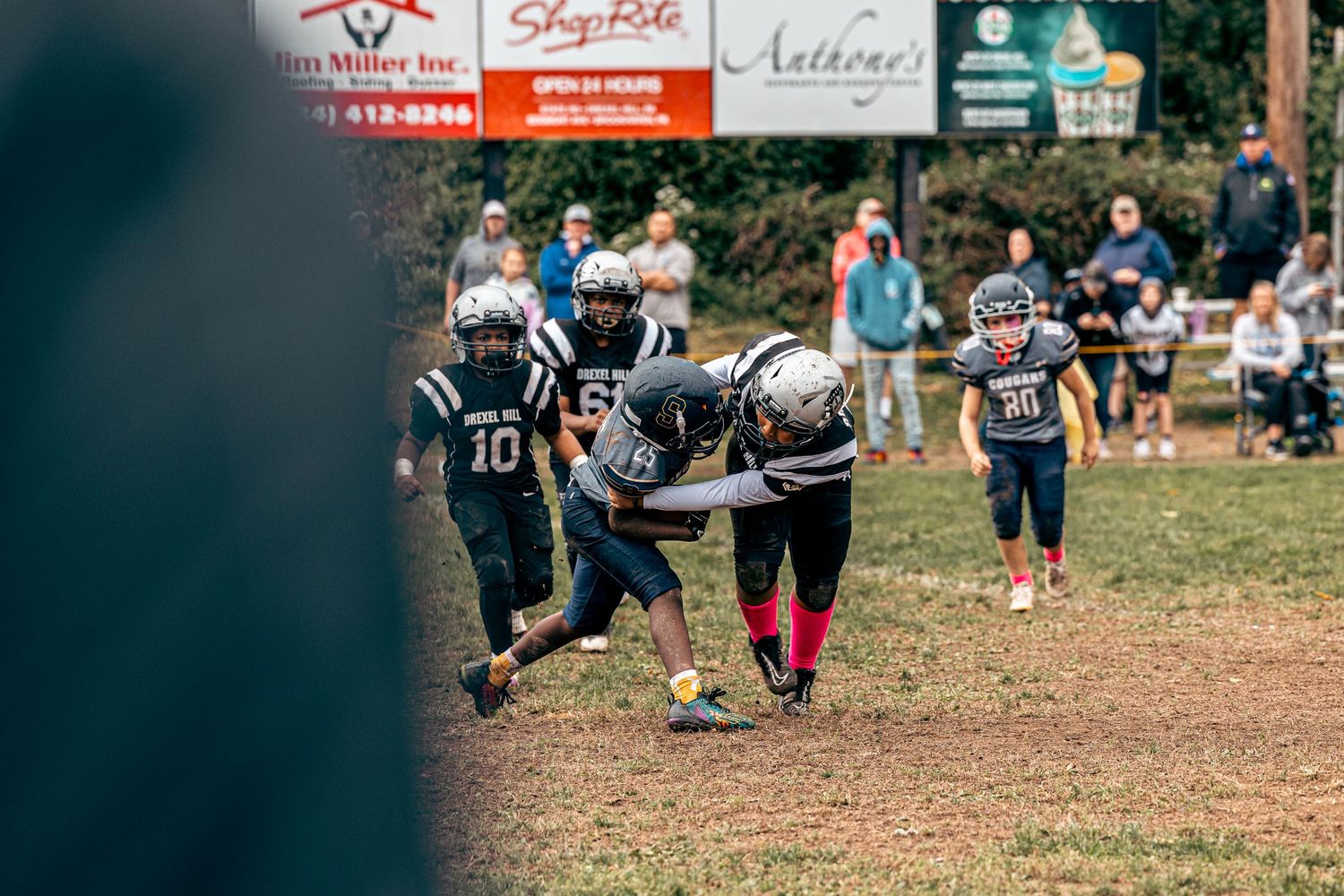 Youth football game in progress with advertising banners visible in the background.
