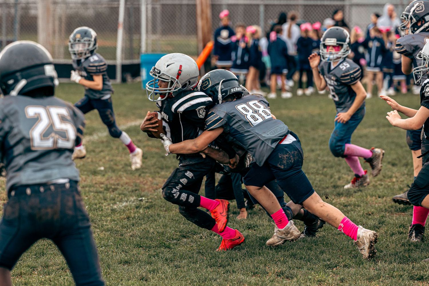 Football players in dark uniforms making a tackle during an intense game play.