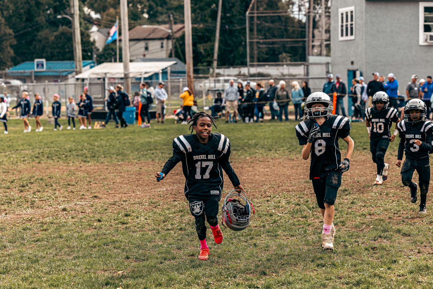 Football players spread out on a grassy field during an outdoor game or practice session.