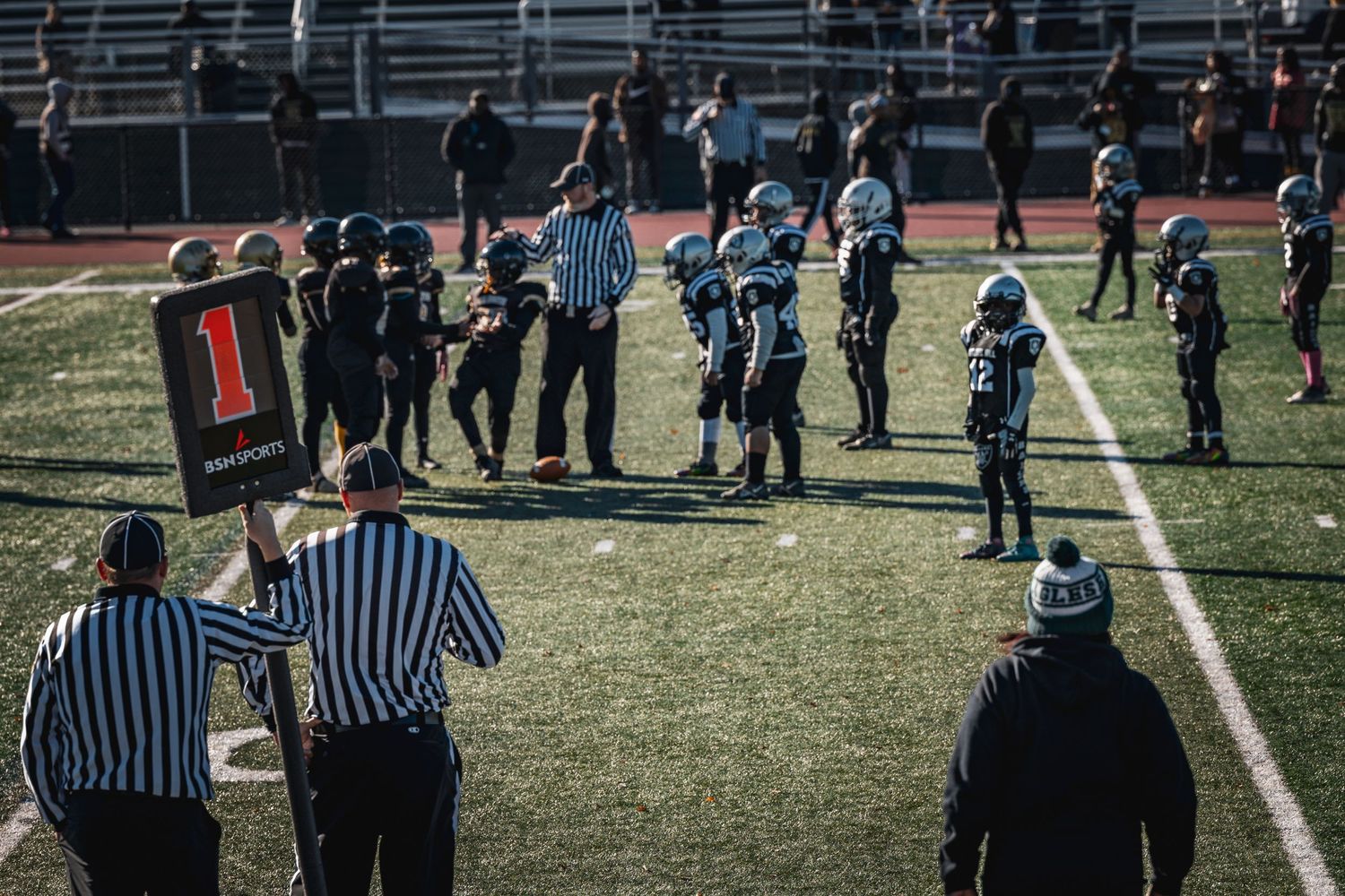 Officials and players gather on football field during sporting event.