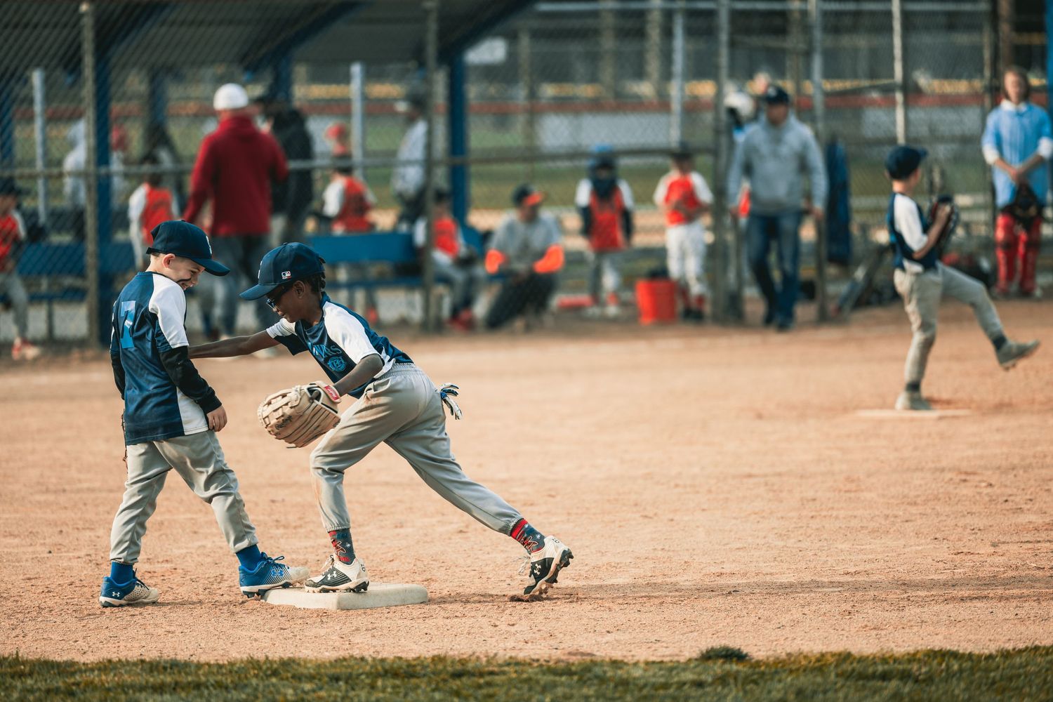 Players running and fielding on a dirt baseball diamond during a game or practice.