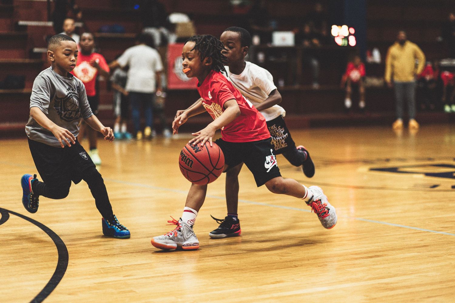 Basketball players in action on a wooden indoor court showing defensive moves.