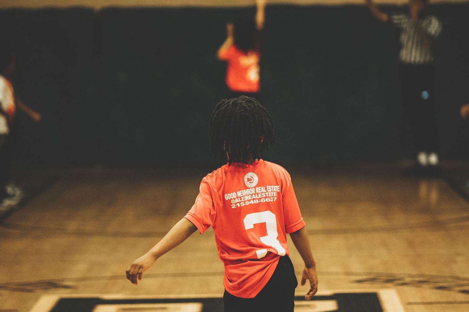 Basketball players in red jerseys practicing drills on an indoor court.