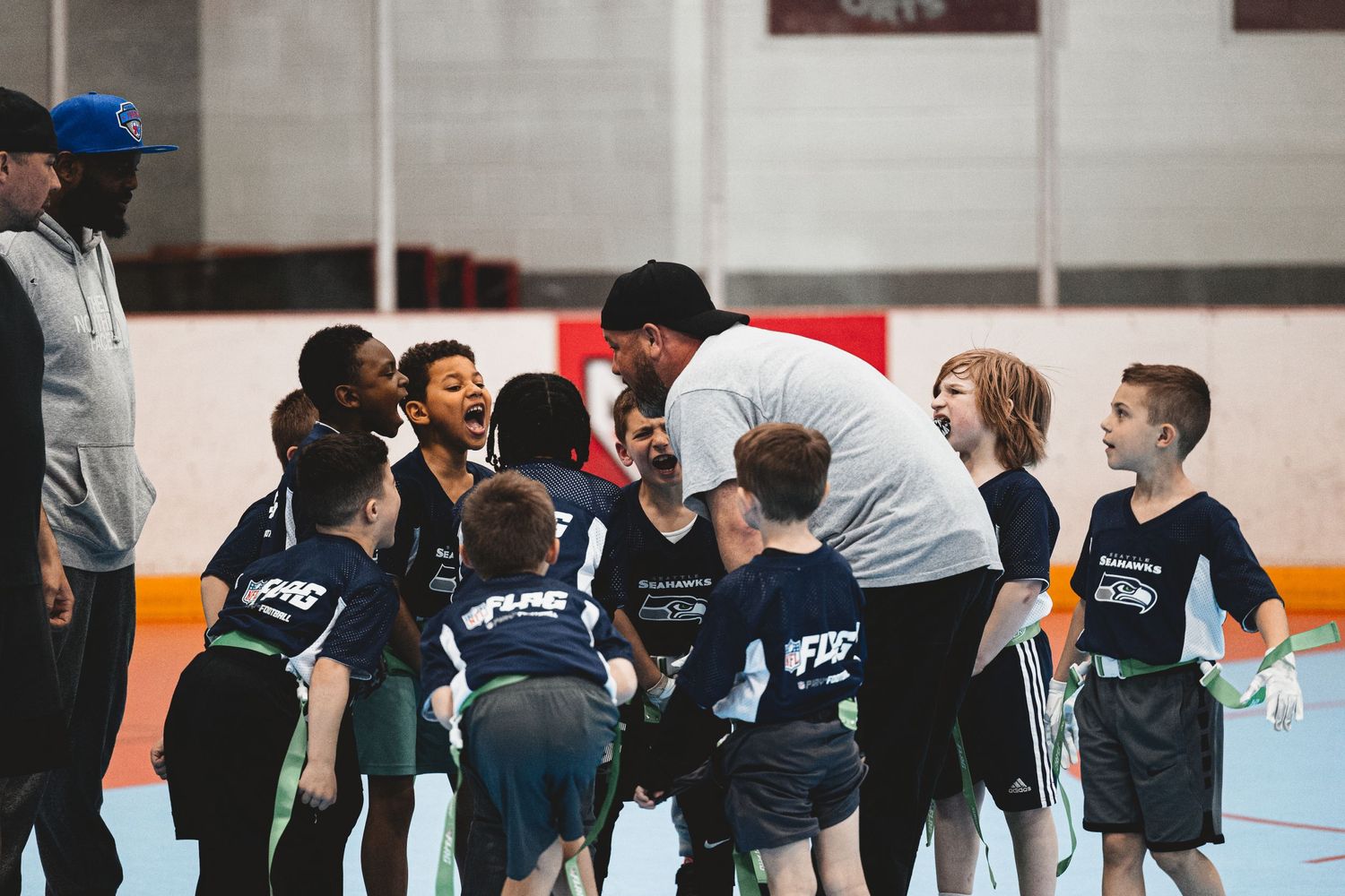 Team huddle of youth athletes in navy blue uniforms during a sports practice.