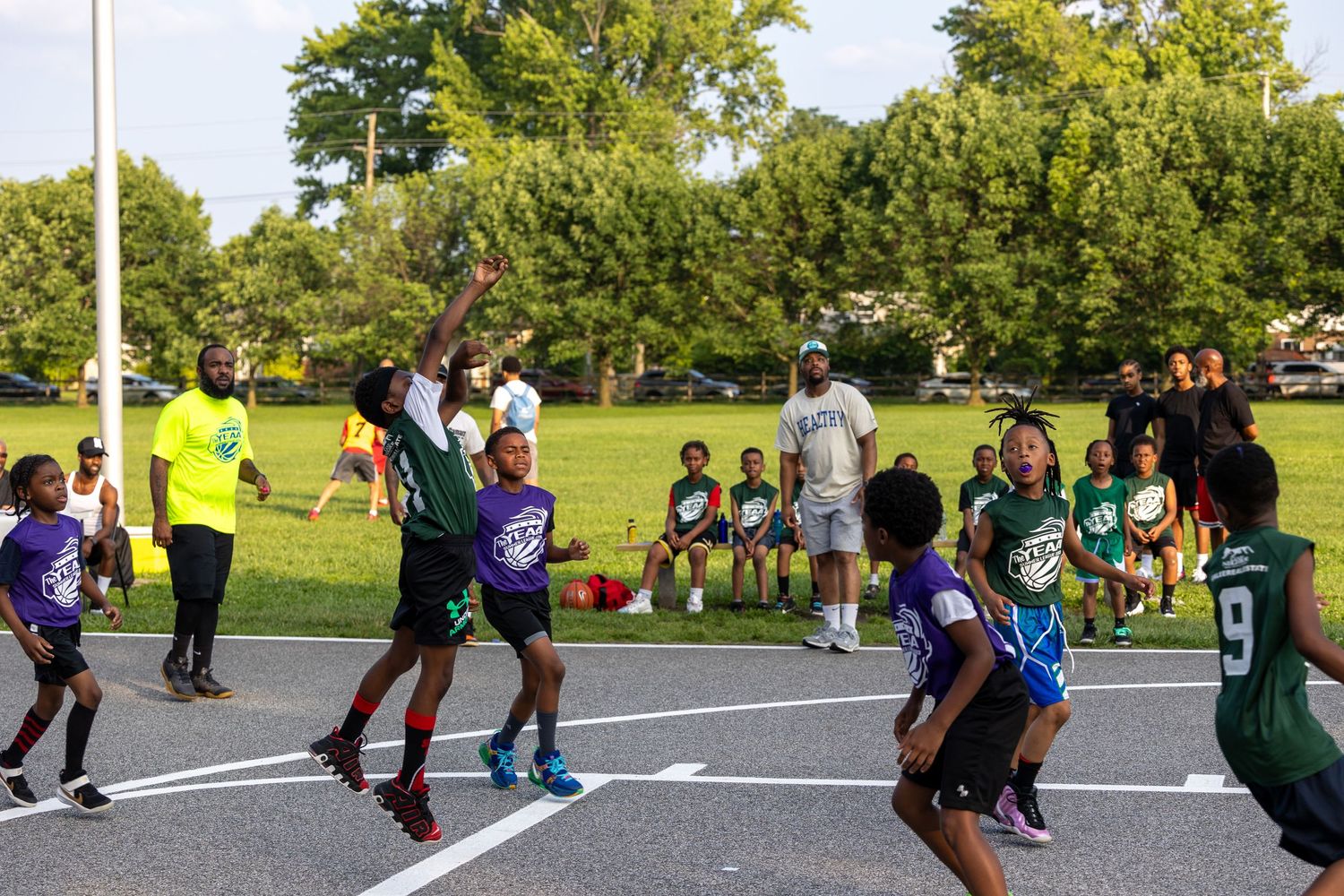 Players jump for the ball during an intense outdoor basketball game.