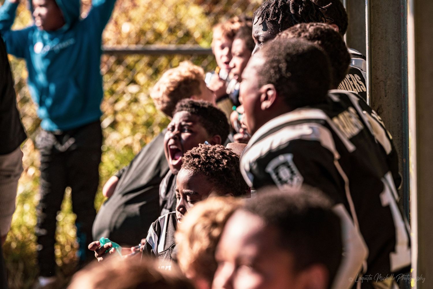 Spectators watching intently from sidelines during outdoor sports event in autumn setting.