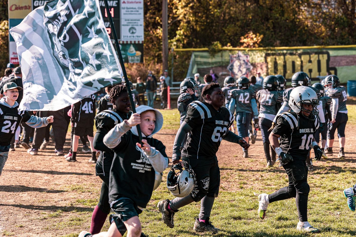 Football players run with team flags during a game day celebration.