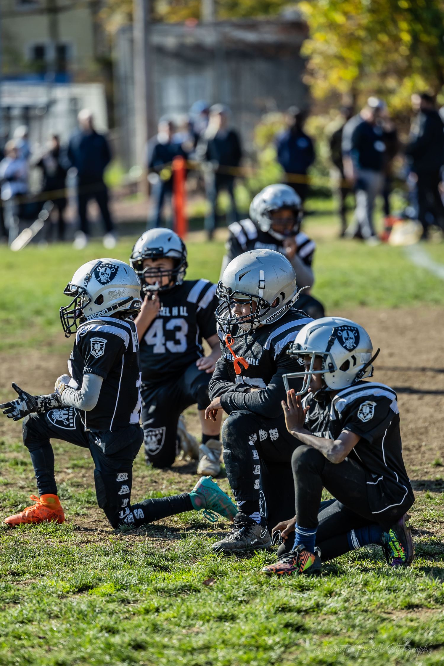 Football players in uniform doing planks during a training exercise on grass.