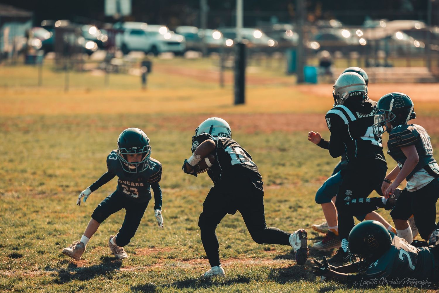 Youth football players executing defensive drills on a grass field.