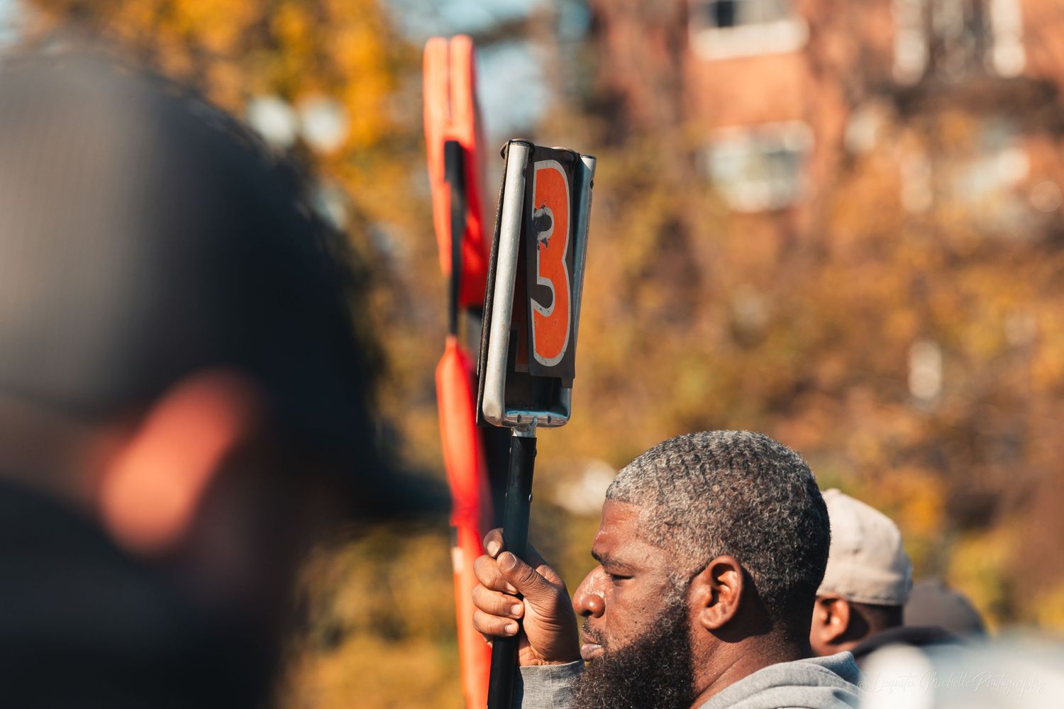 Football players performing stretching exercises on the sidelines during fall practice.