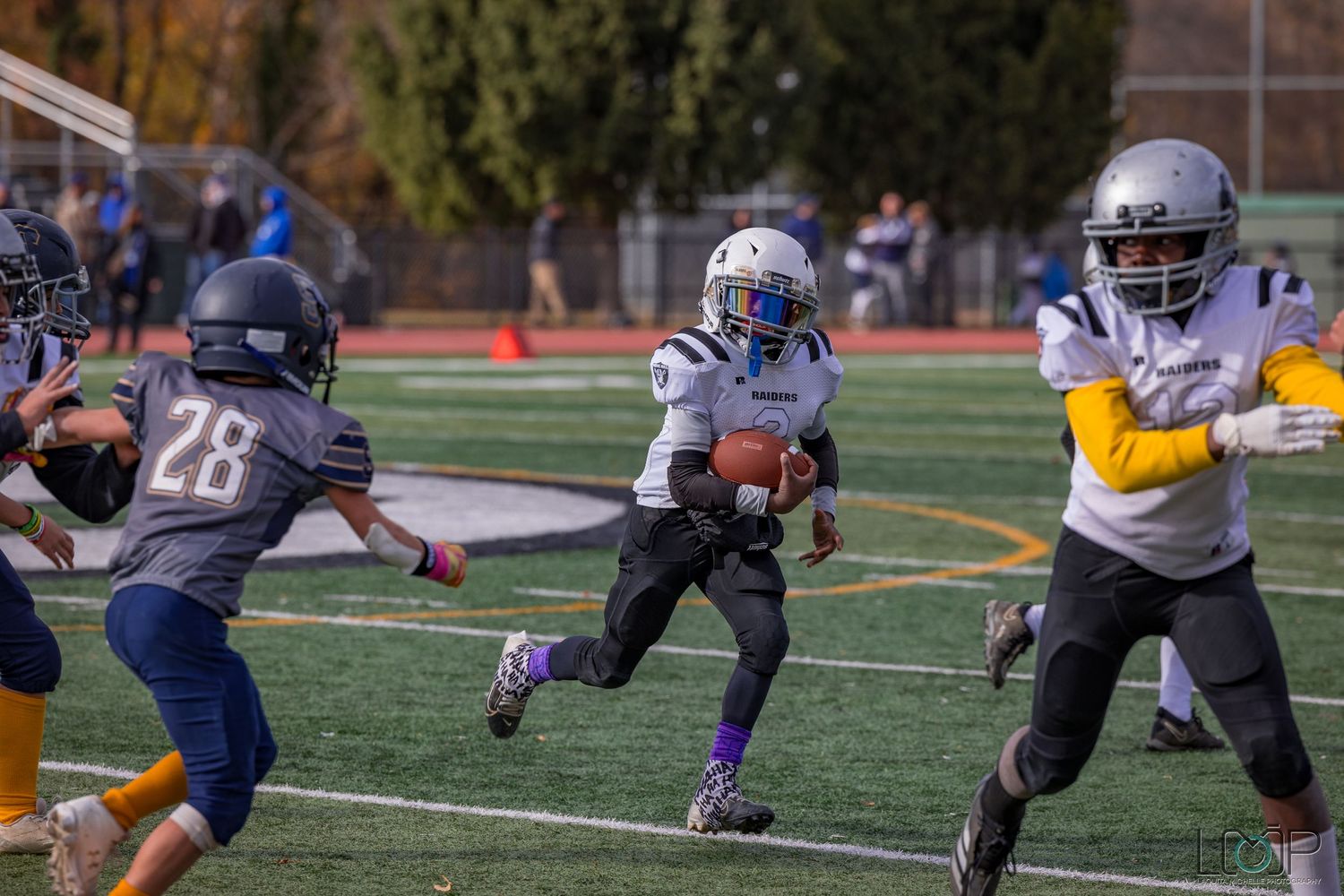 Football players in protective gear practicing defensive positions on a turf field.