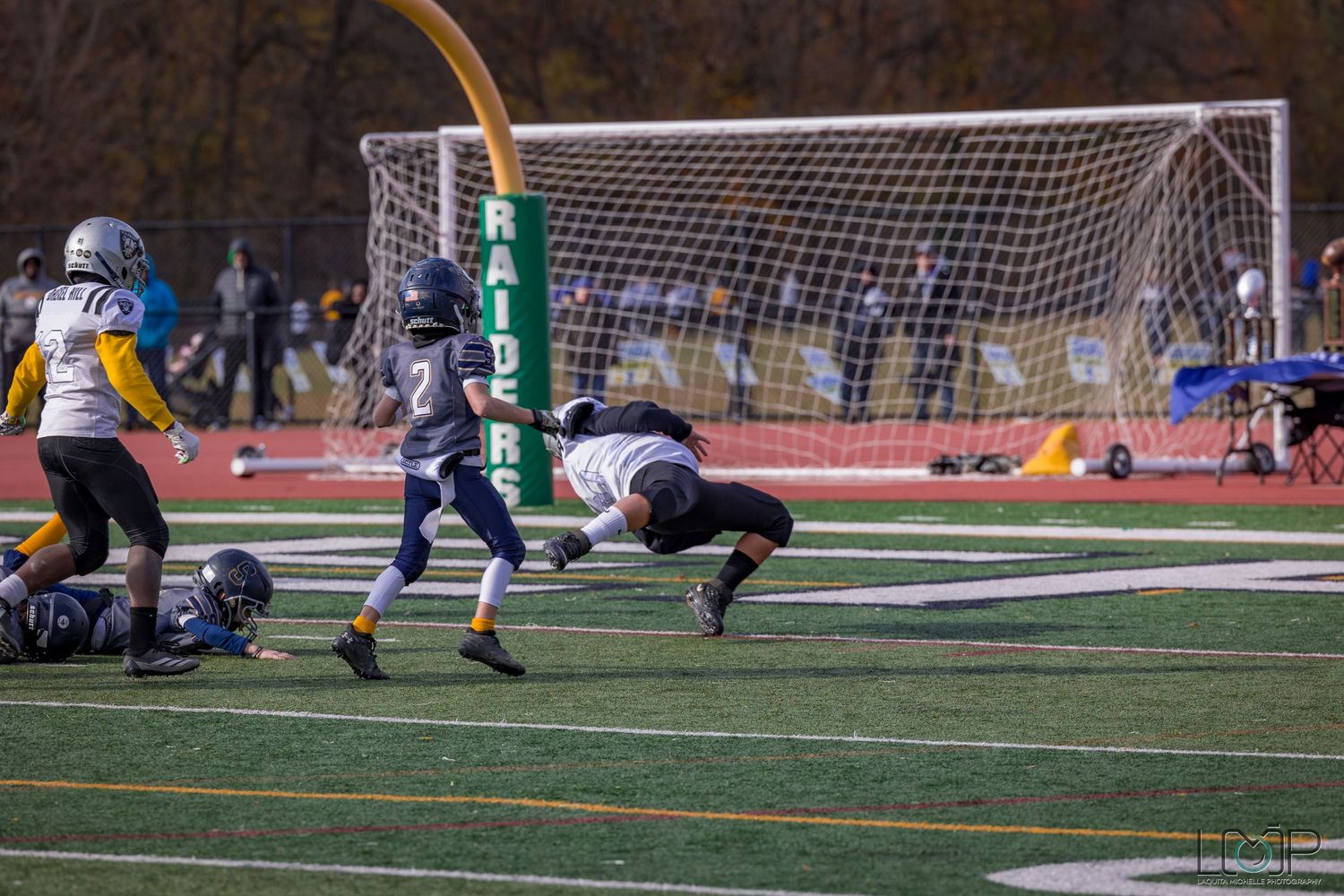 Soccer goal net on sports field with players during competitive match in fall season.