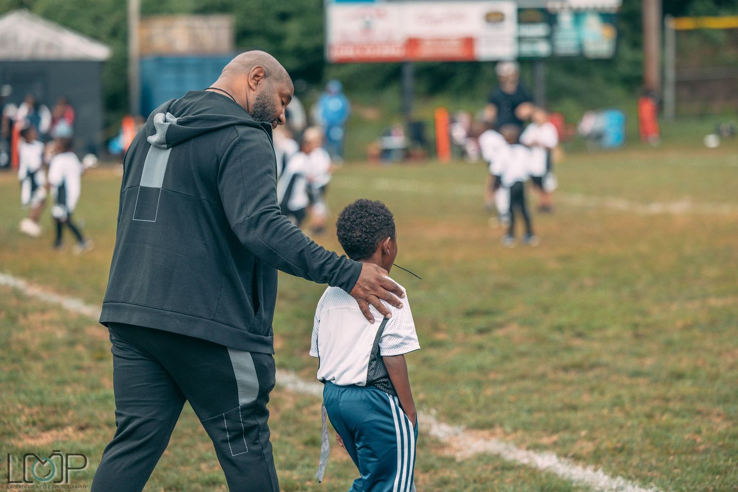 Coach providing guidance to young player on sports field during practice.